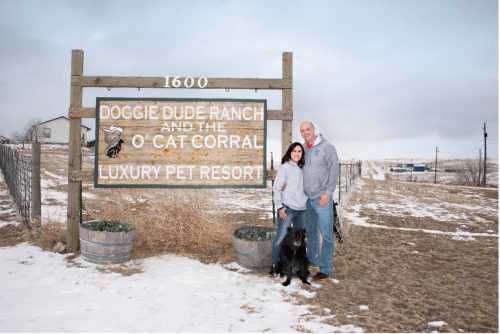 Dave and Melanie Knudtson standing by Doggie Dude Ranch and O'Cat Corral sign